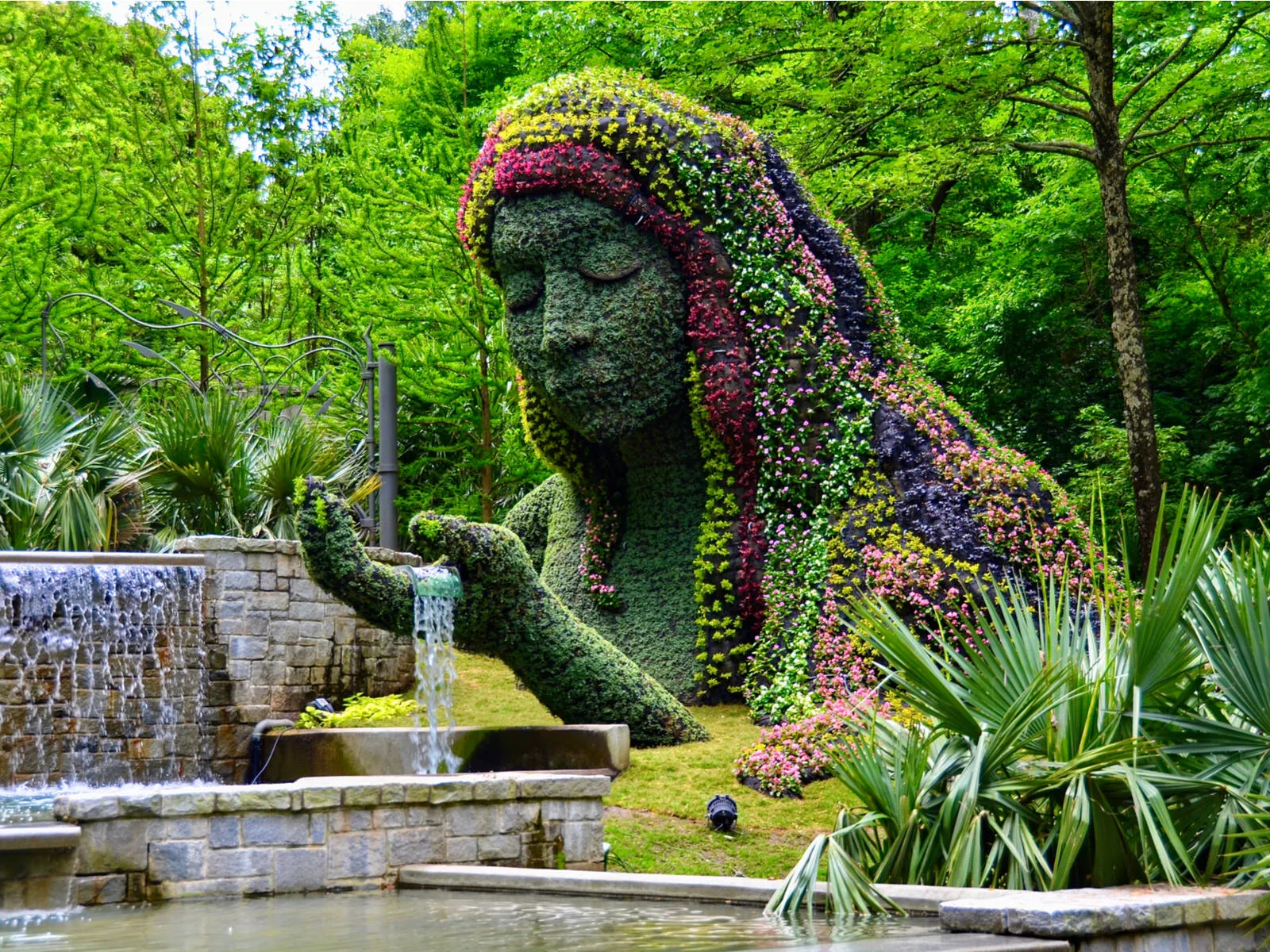 Earth Goddess sculpture holding a stream of water and decorated with various colored plants in Atlanta Botanical Garden, one of the most beautiful places in the US