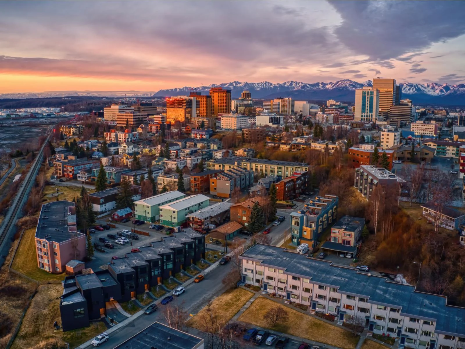 Aerial view of the peaceful Anchorage in Alaska during sunset with snowy mountains in background, one of the most beautiful cities in the US
