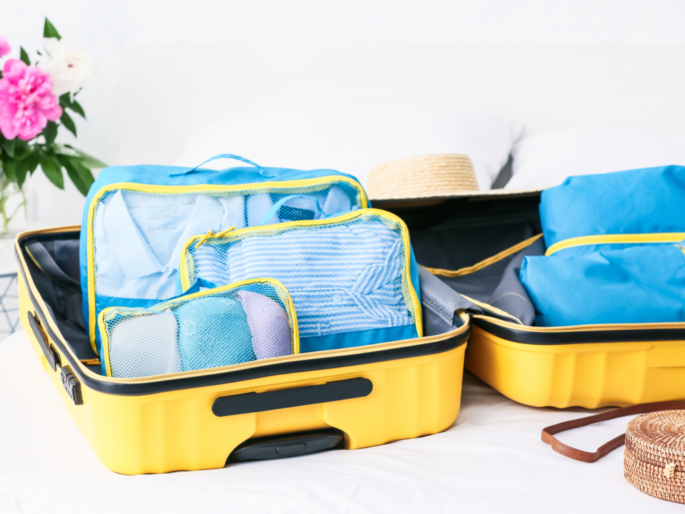 Yellow suitcase with some of the best travel organizers holding contents, blue in color