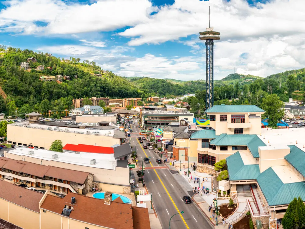 an aerial view showing many best things to do in gatlinburg, tennessee in a clear day, with a bunch of structures and a light traffic street.