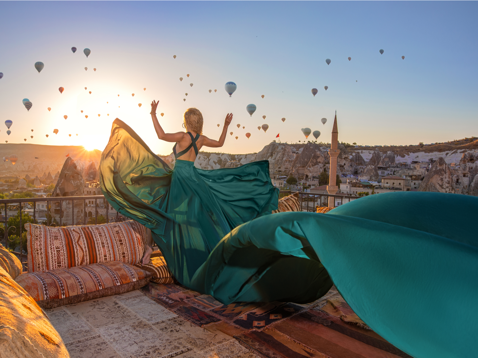 Gorgeous and thin woman holding her hands up overlooking the hot air balloon festival during the best time to visit Turkey