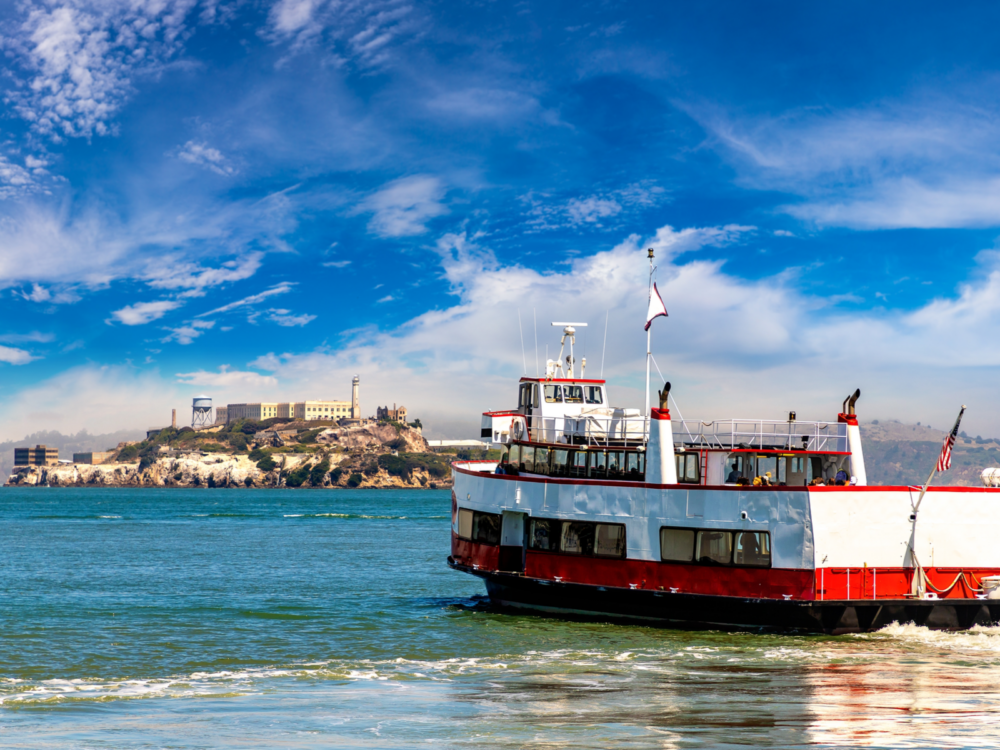 Few people onboard a white-red passenger ferry heading towards Alcatraz Island, one of the best things to do in California