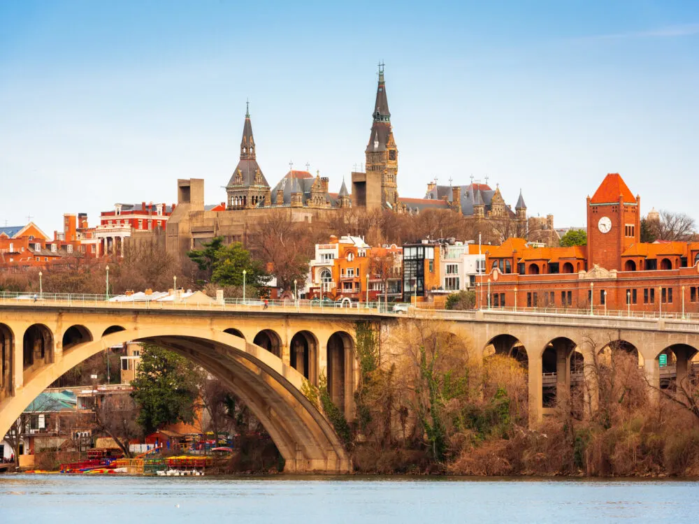 A view of the historic Georgetown District, one of the best things to do in Washington D.C., pictured a bridge over Potomac River and old structures