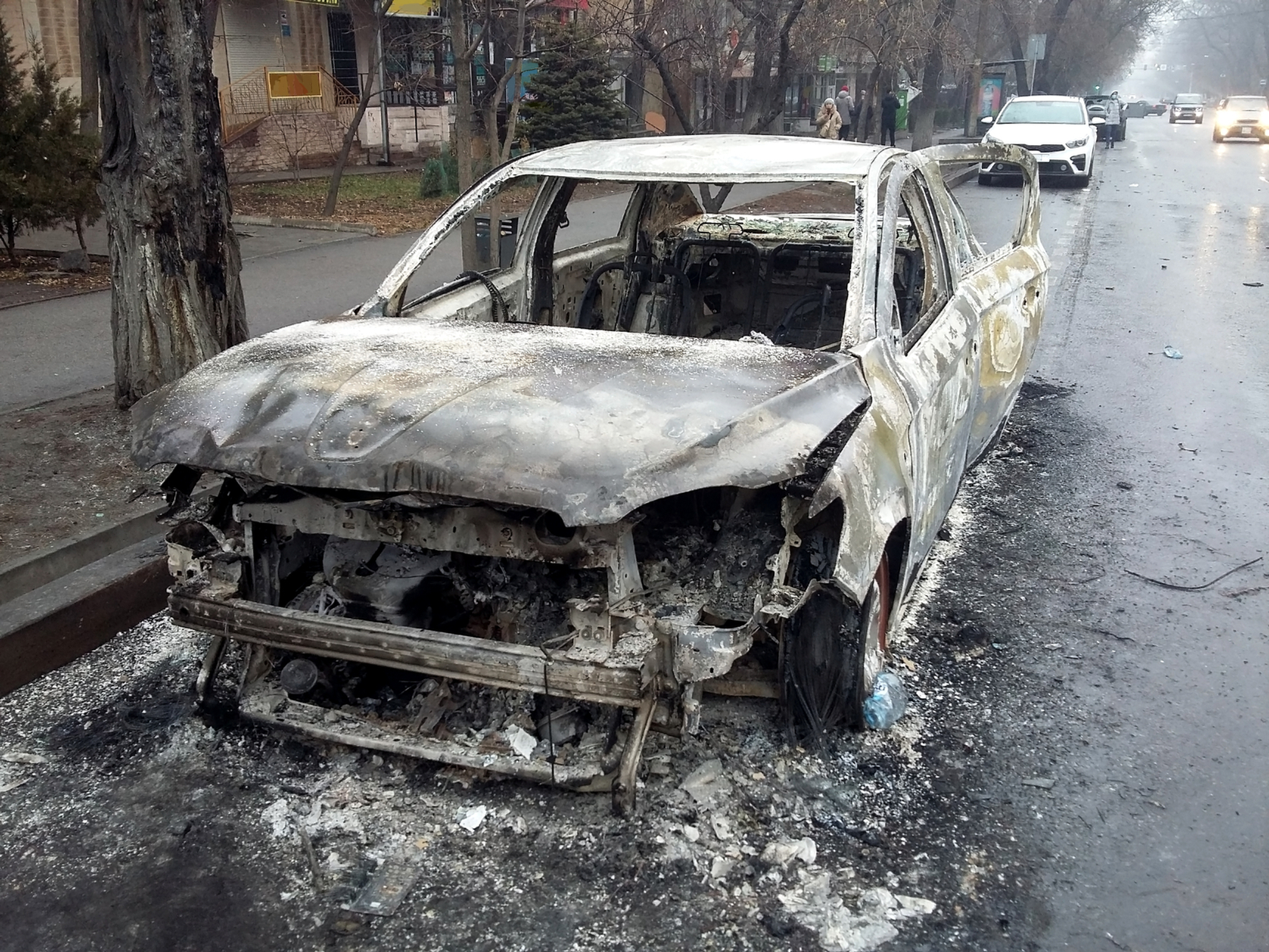 Almaty Kazakhstan photo of a burned out car in the road as the result of a terrorist attack for piece titled Is Kazakhstan Safe