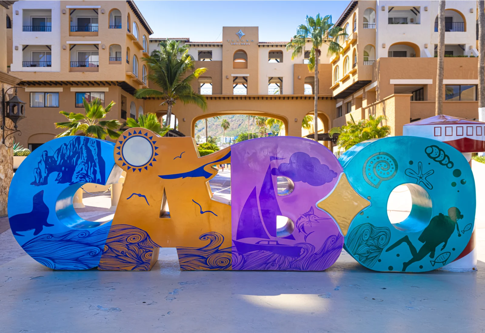 A multicolored sign that says Cabo sits in front of some of the best all-inclusive resorts in Cabo San Lucas