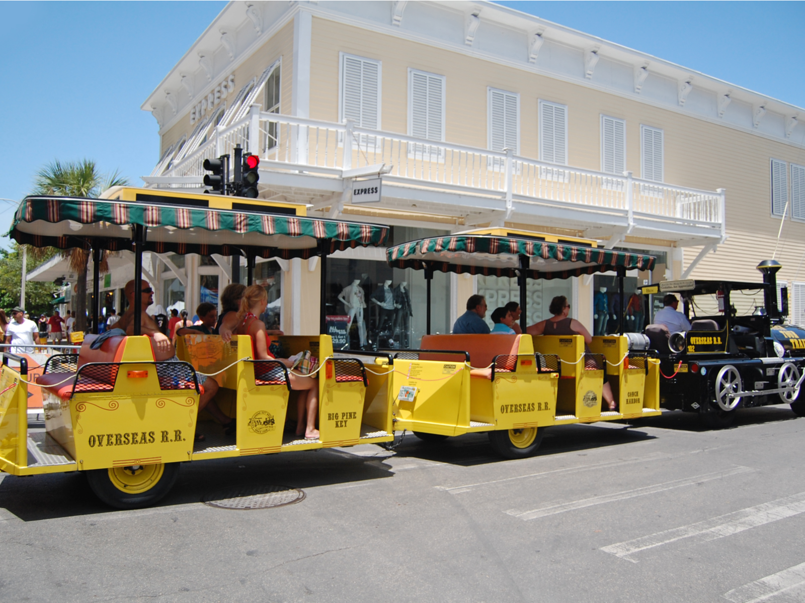 Several tourist, touring over one of the best things to do in Key West, riding the Conch Tour Train, and several people walking in backdrop