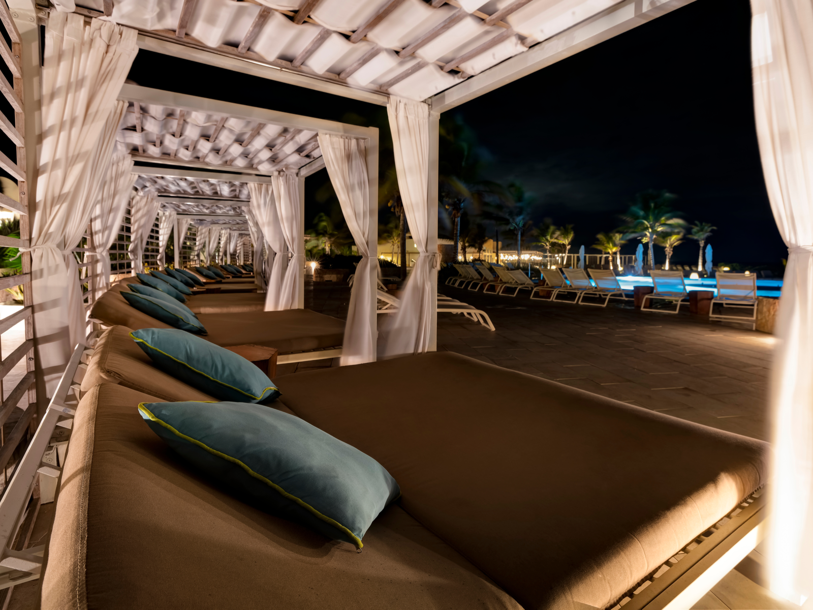 Empty lounge in a cabana beside lit Helios Infinity Pool at night in Grand Palladium White Sand Resort & Spa, a piece on the best all-inclusive resorts in Mexico
