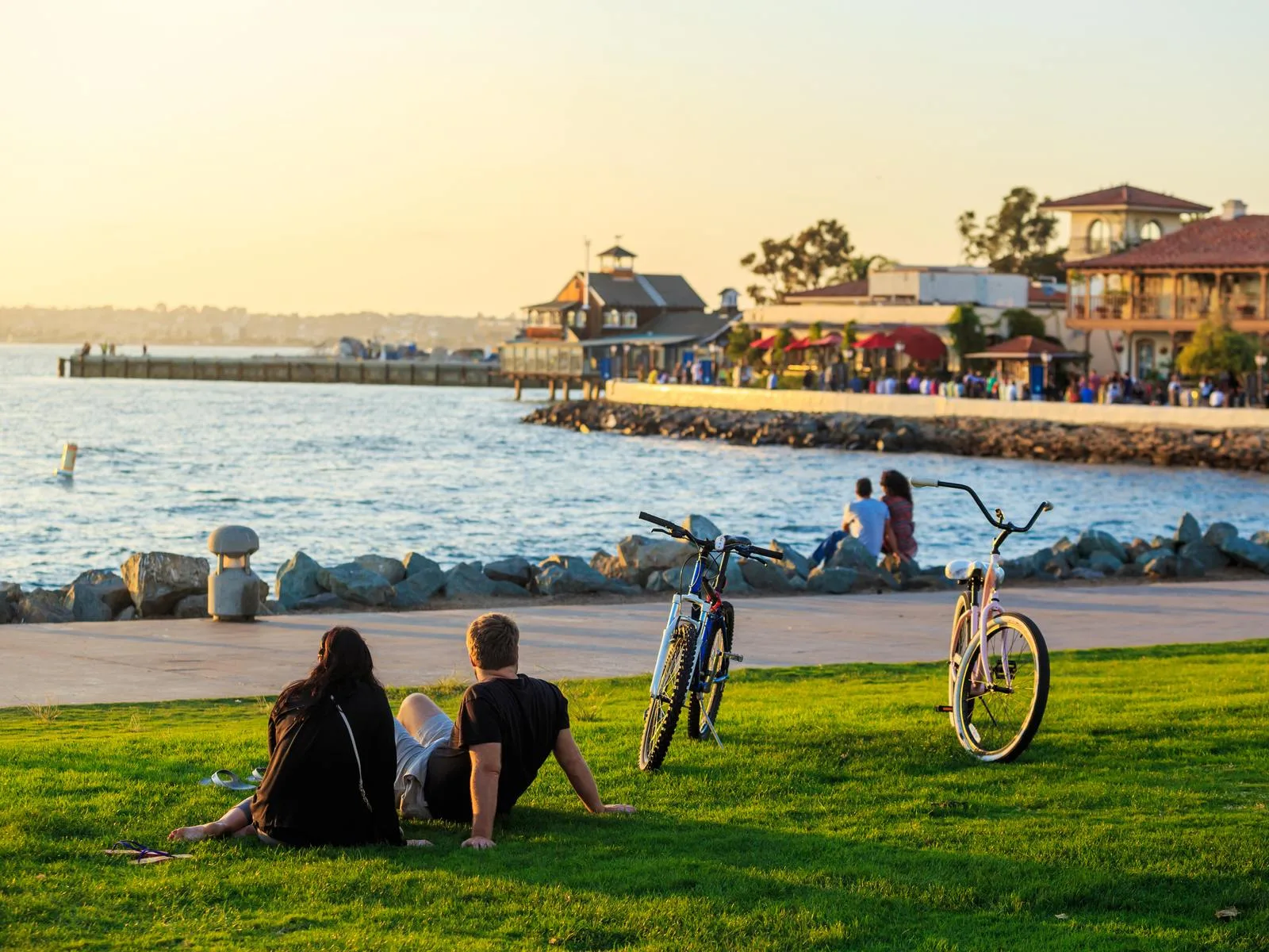A young couple parked their bikes to sit on the grass and look at the ocean during the best time to visit San Diego