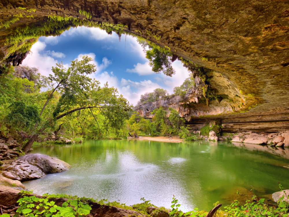 Fantastic wide view on Hamilton Pool sink hole in Texas, named one of the most beautiful places in the US, with emerald water and moss and ferns on its rocks