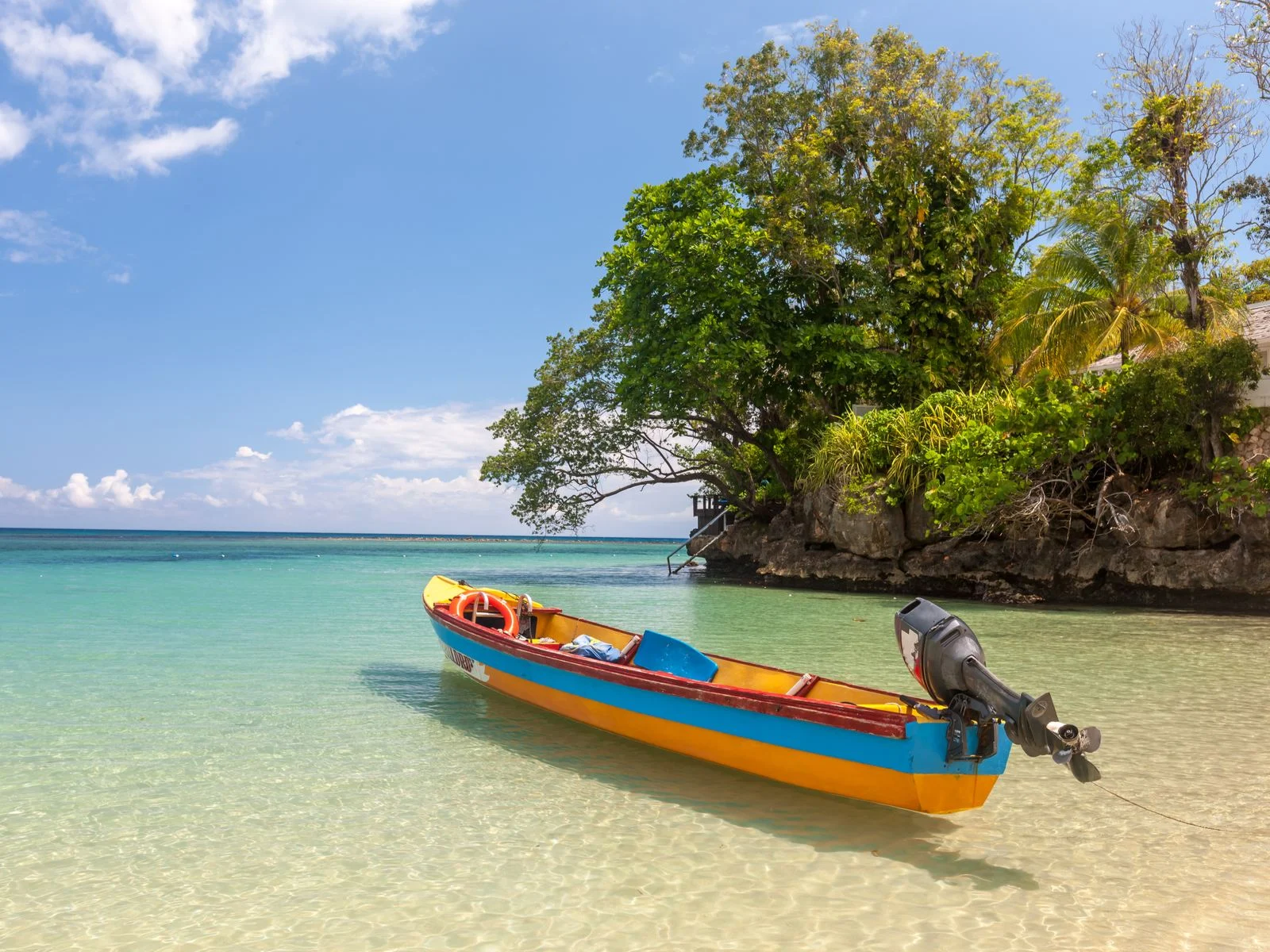 Boat floating on the crystal-clear ocean water during the cheapest time to visit Jamaica