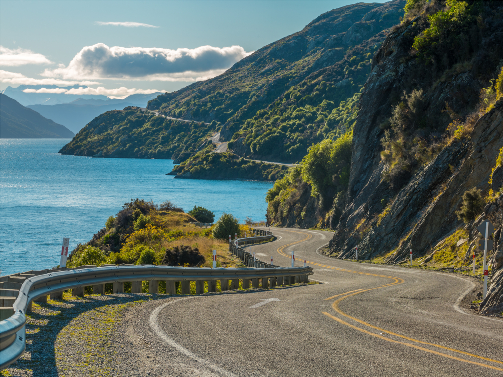 Road along Lake Wakatipu during the best time to visit New Zealand with warm weather and clear skies with few clouds