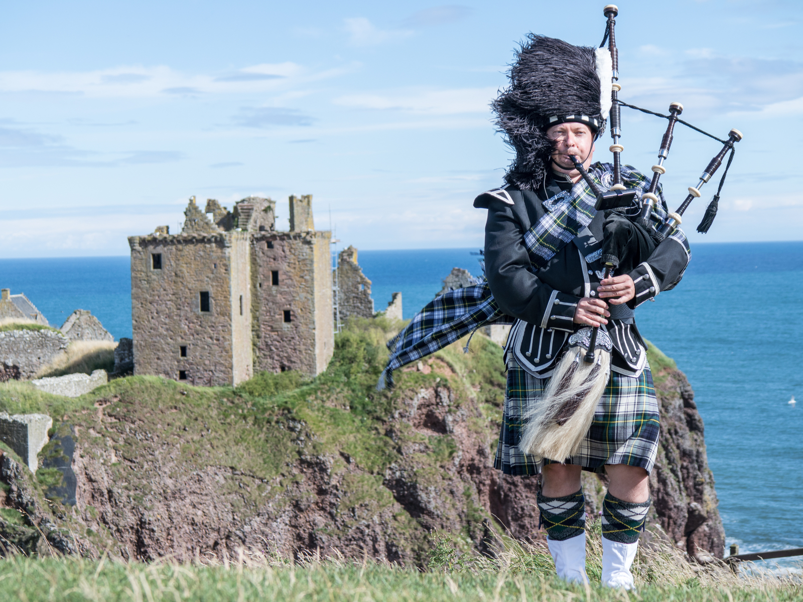 Traditional Scottish bagpiper in full dress during Summer, the best time to visit Scotland