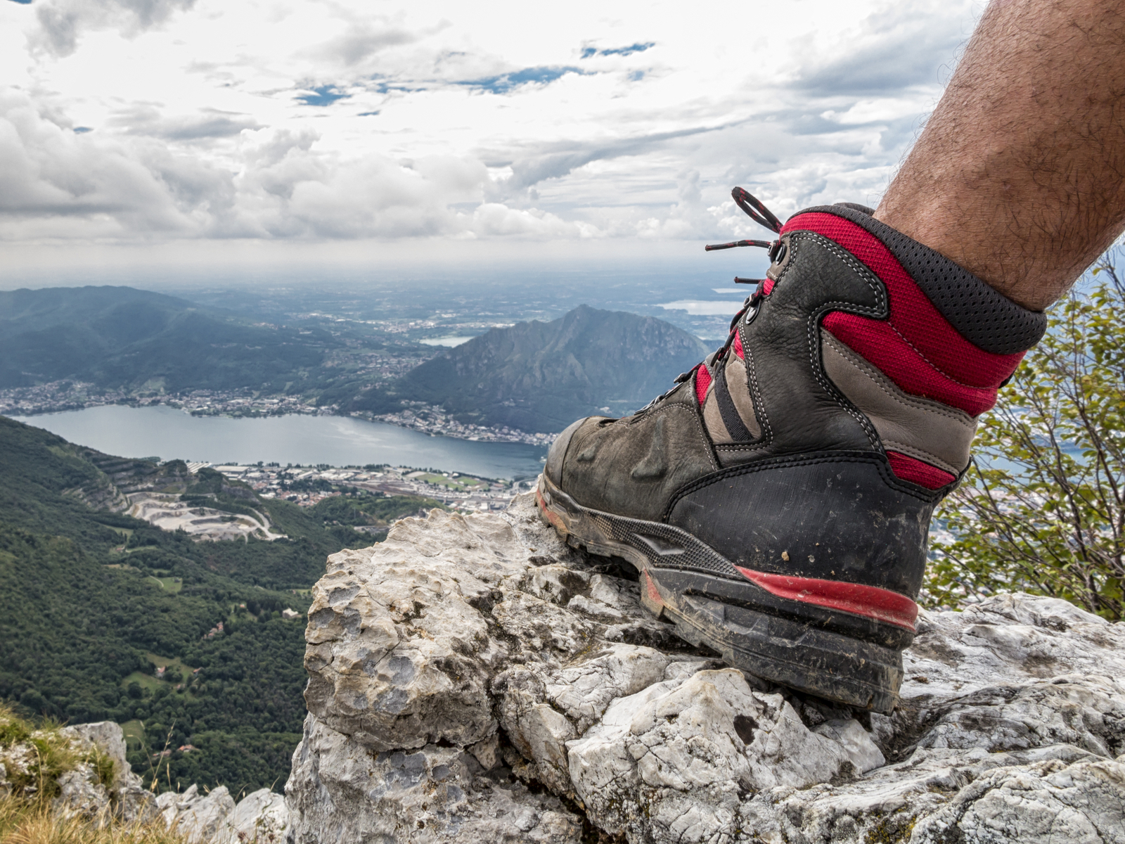 Guy wearing a pair of the best hiking boots while putting his foot on the rocks on a mountain