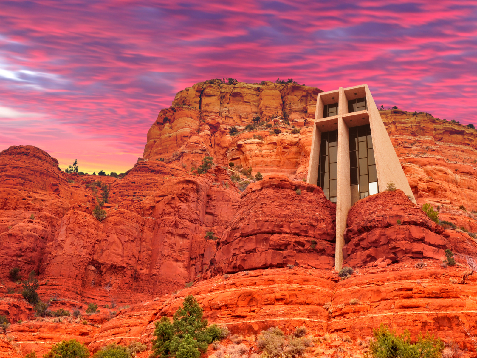 Holy Cross Chapel built into the red cliffside with a gorgeous red sky above