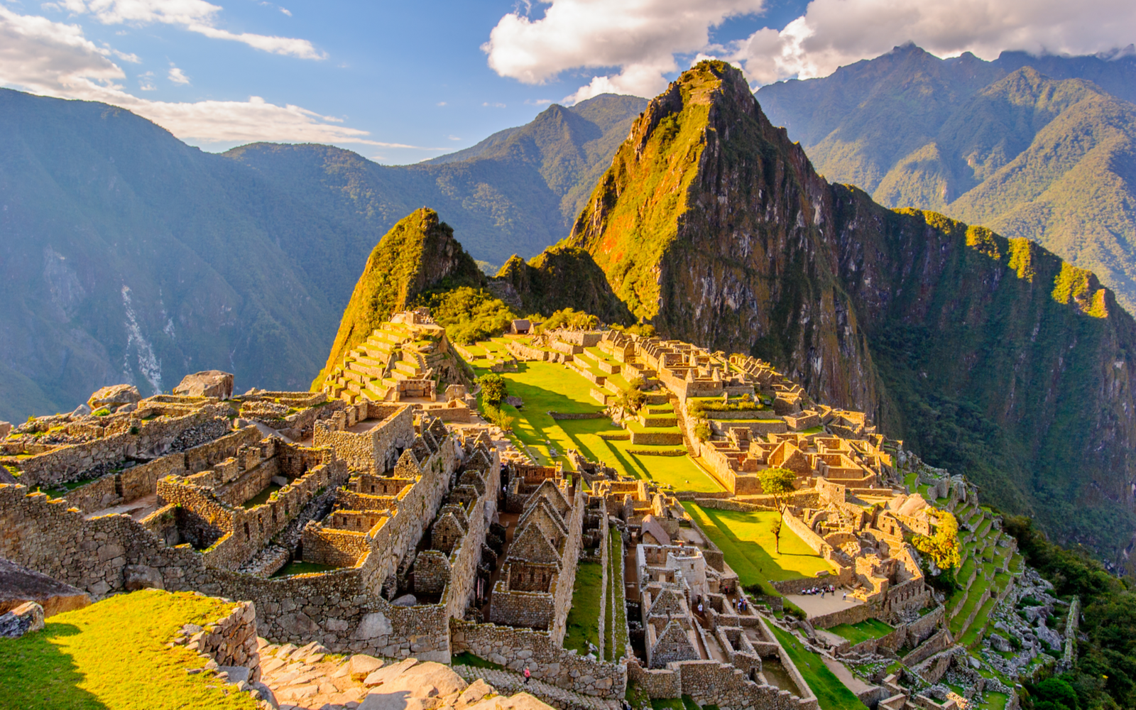 Hilltop ruins in Peru pictured during the best time to visit Machu Picchu with clouds overhead and warm weather