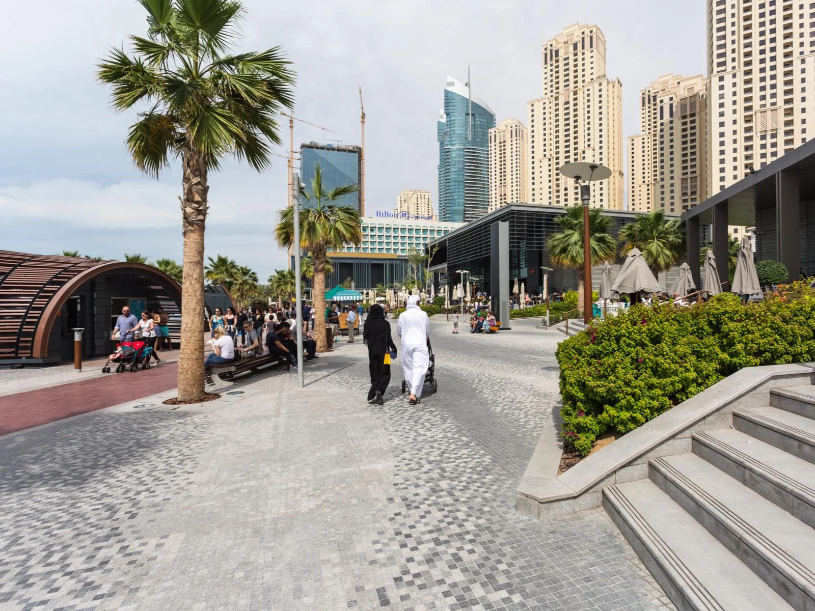 View of Jumeirah Beach Residence and people walking on the sidewalk for a piece titled Is Dubai Safe