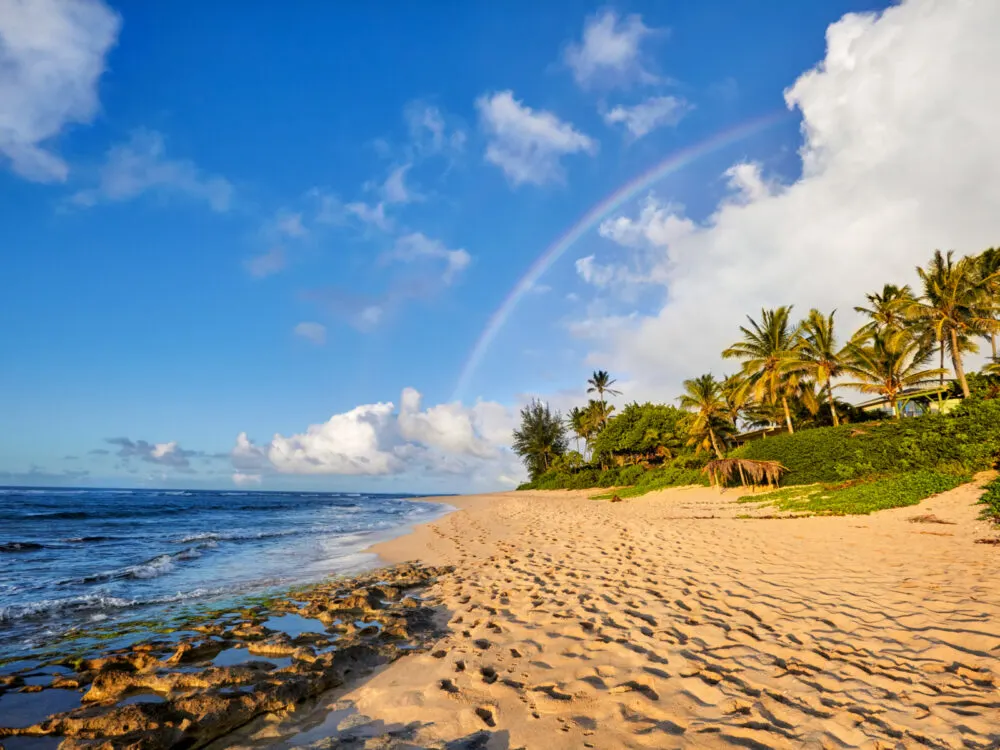 Rainbow over the scenic view of Sunset Beach on the North Shore during the cheapest time to visit Oahu