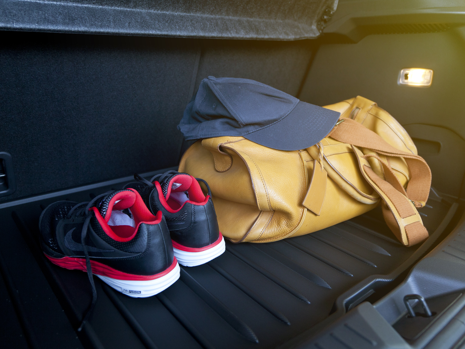 Image of a leather bag an sport shoes in the trunk of a car for a piece on the best weekender bags