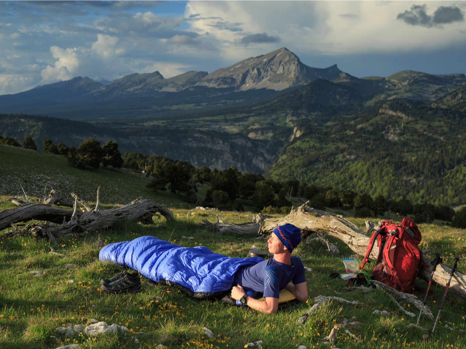 Hiker preparing for a hike while using his backpack sleeping bag on the side of a hill