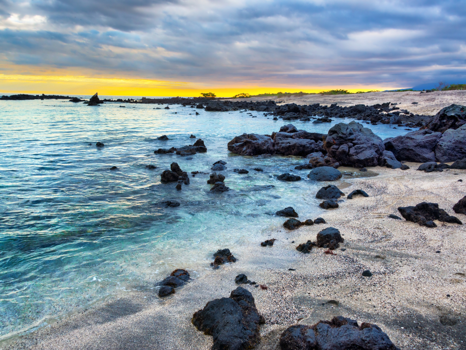 Rocks on the beach pictured with a sunrise during the best time to visit the Galapagos Islands