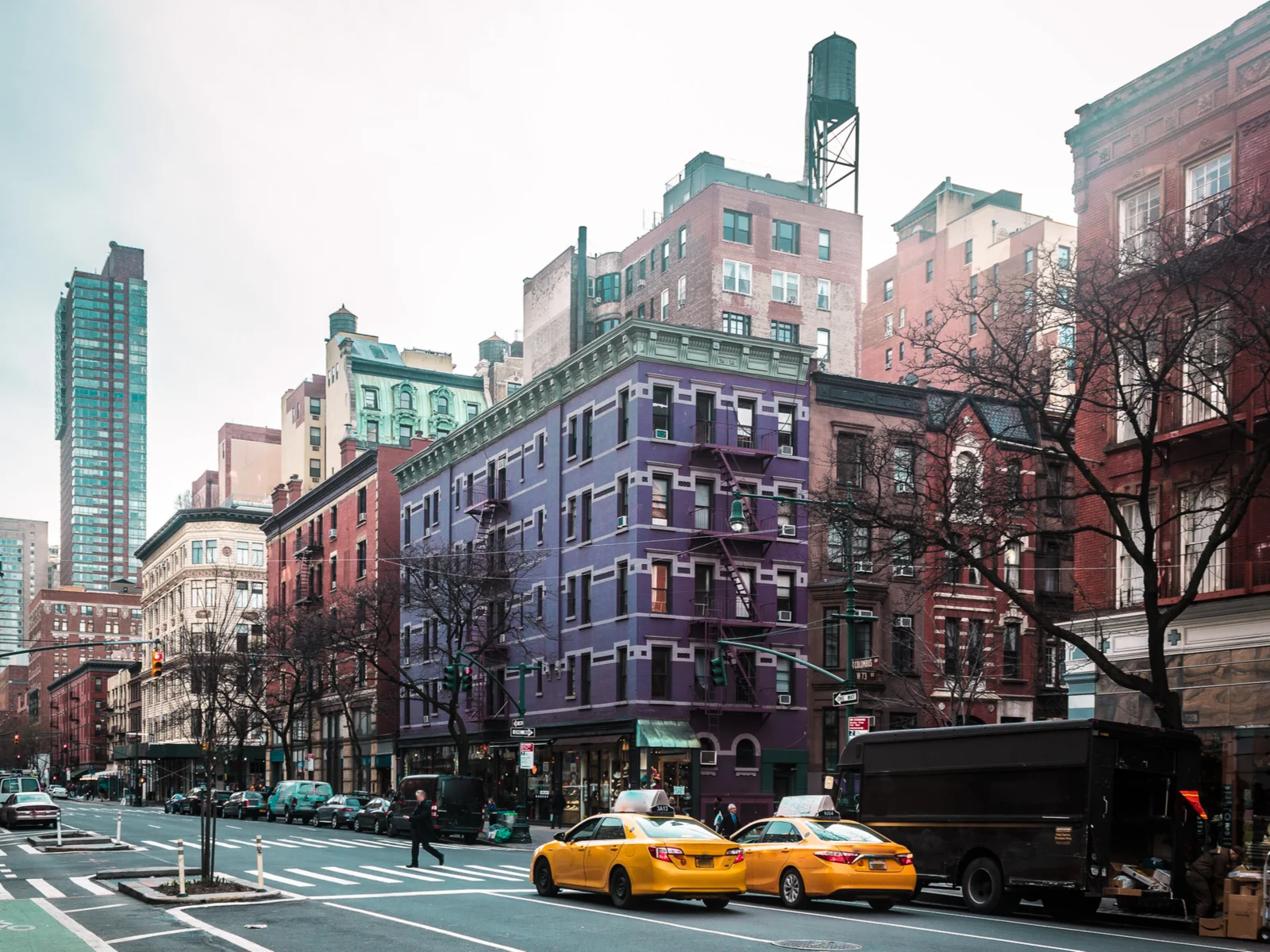 Photo of buildings and homes with taxi cabs on a busy street in one of the best places to stay in New York City, the Upper West Side