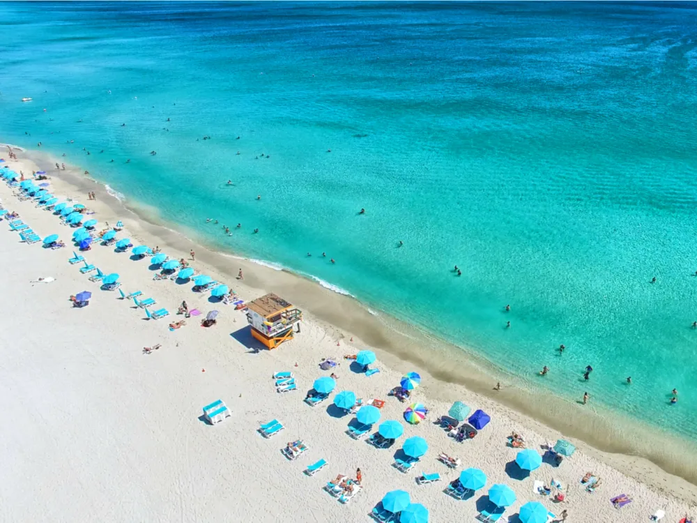 Visitors swimming at the turquoise waters and sunbathing at the shore of South Beach in Miami, Florida, one of the most iconic places in America