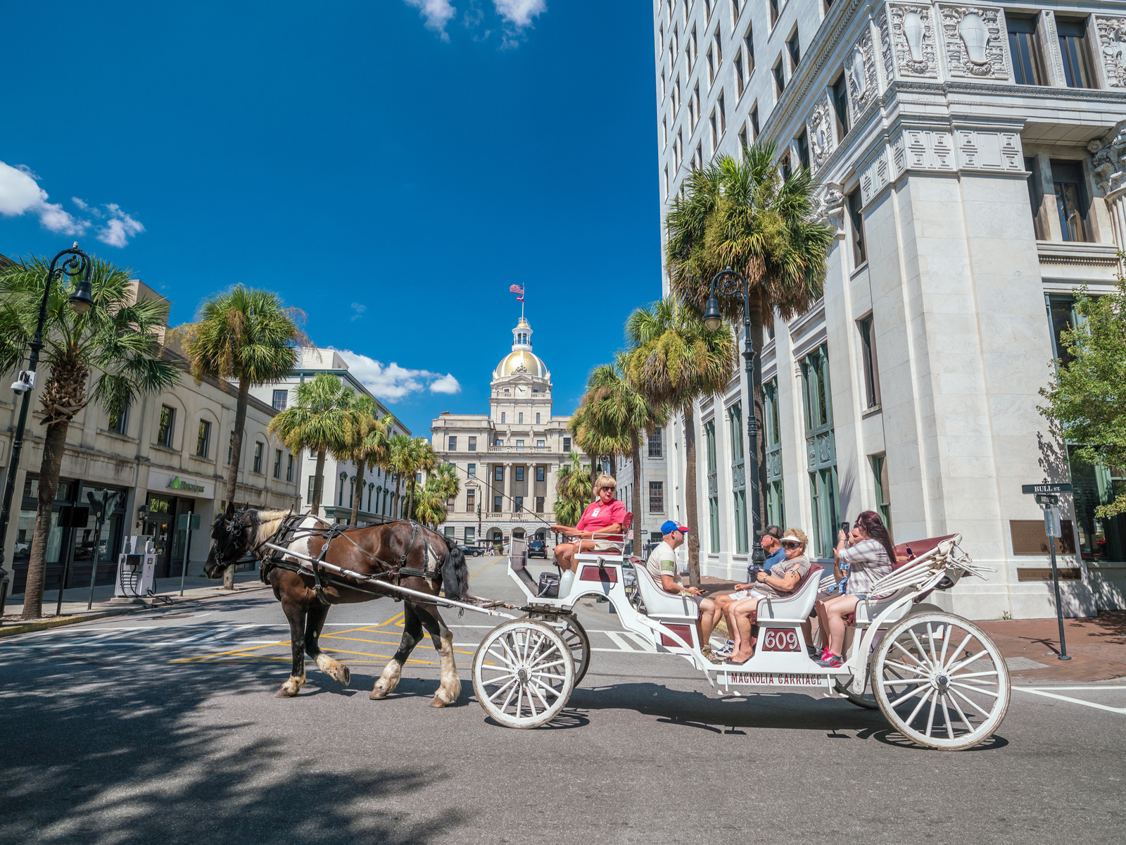 A family of tourists riding a traditional carriage on the street in Savannah, Georgia, considered one of the most beautiful cities in the US