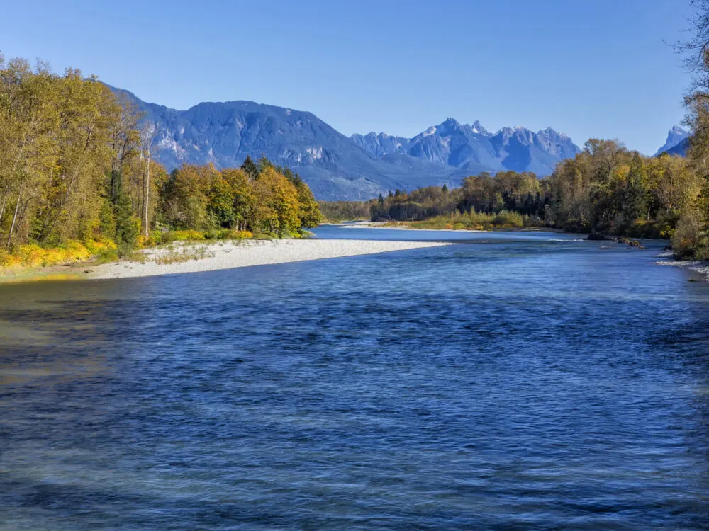 Clear and cold water of Skykomish River with bluish Gunn Peak and Mount Index in the background, one of the most iconic Lord of the Rings filming locations