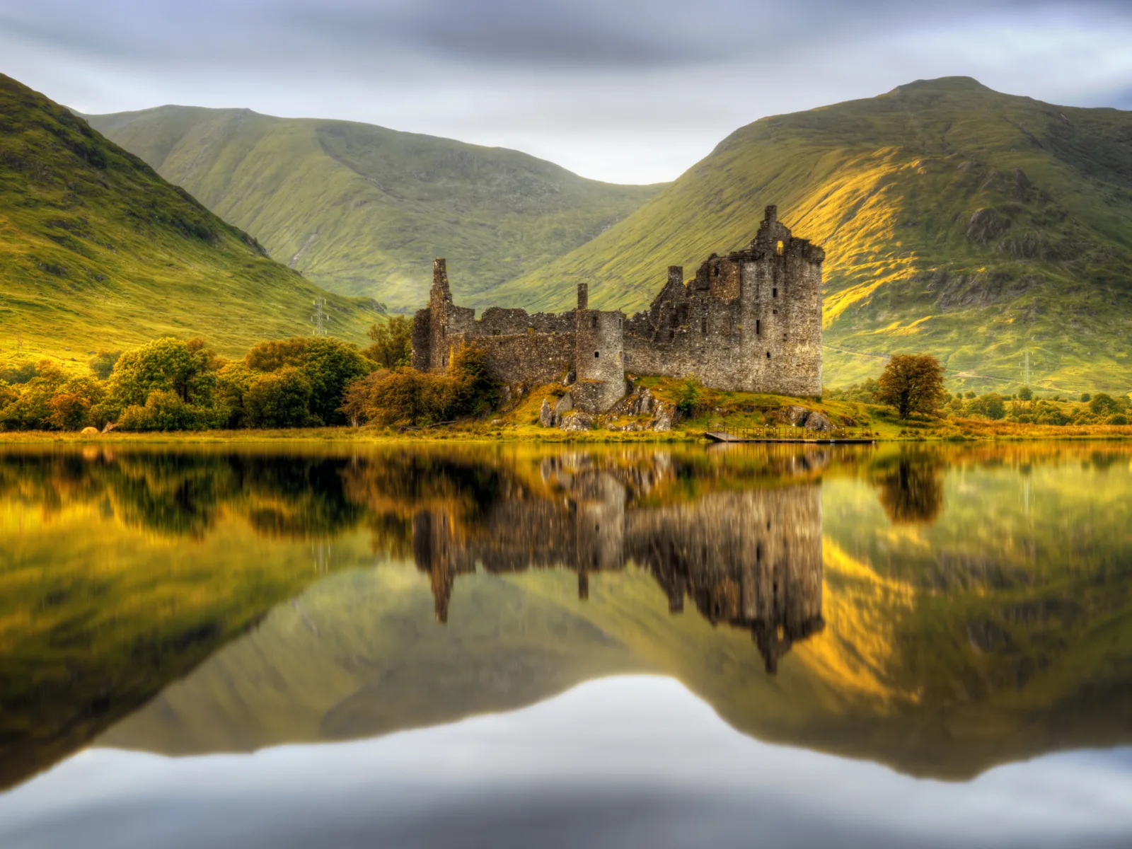 Kilchurn Castle reflecting in the water in Loch Awe at Sunset during the cheapest time to visit Scotland