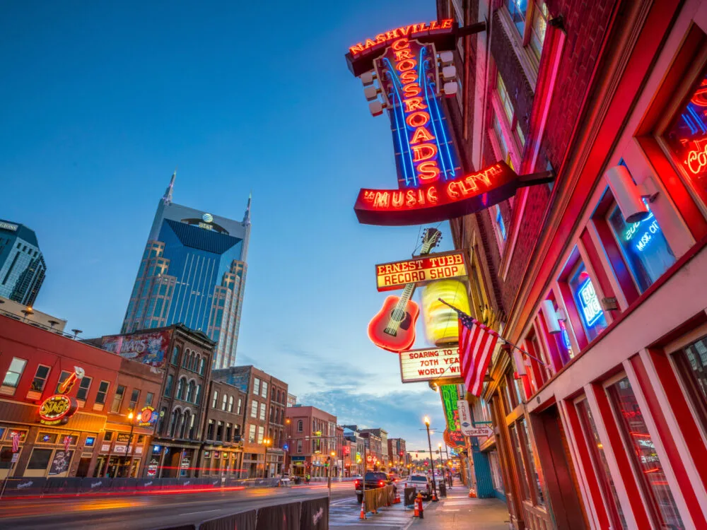 Neon signs on Lower Broadway as seen at dusk during the best time to visit Nashville with clear skies and warm weather