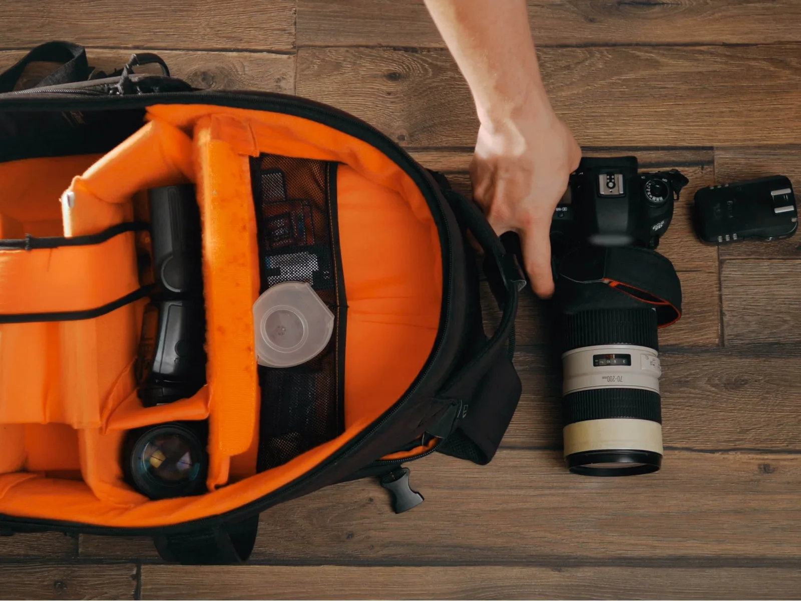 Photographer with an orange camera bag putting his tools away