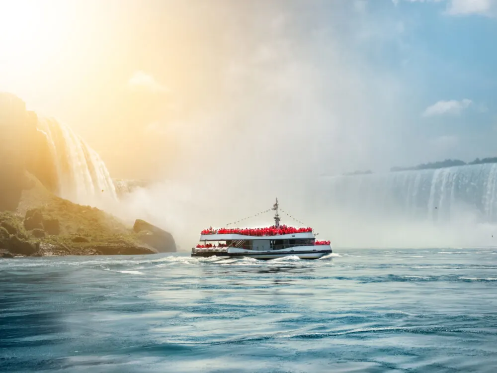 Image of a boat on the side of the shore with sun reflecting off the water during the best time to visit Niagara Falls
