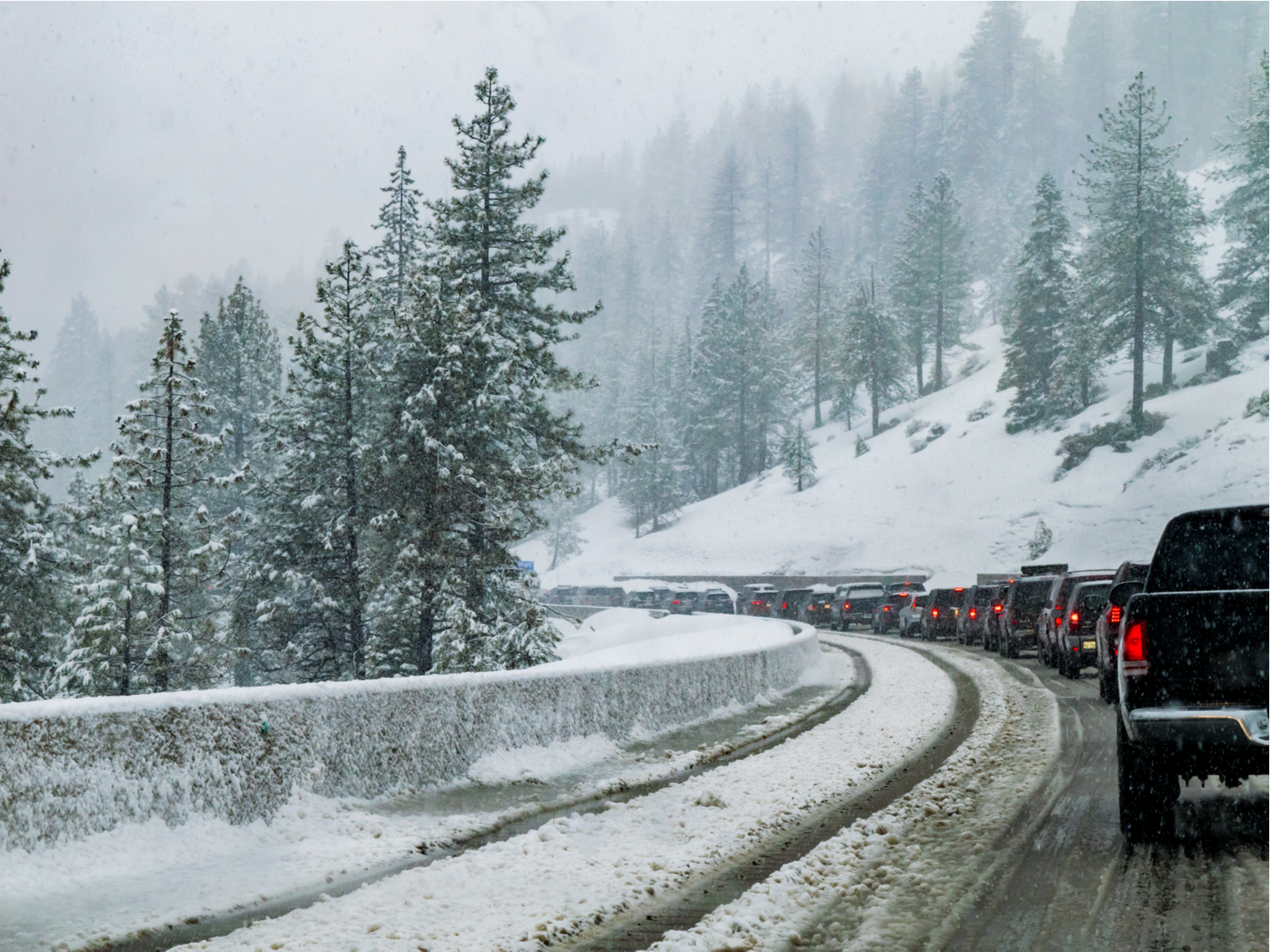 Trucks lined up on the highway in the winter with lots of snow during the worst time to visit Lake Tahoe