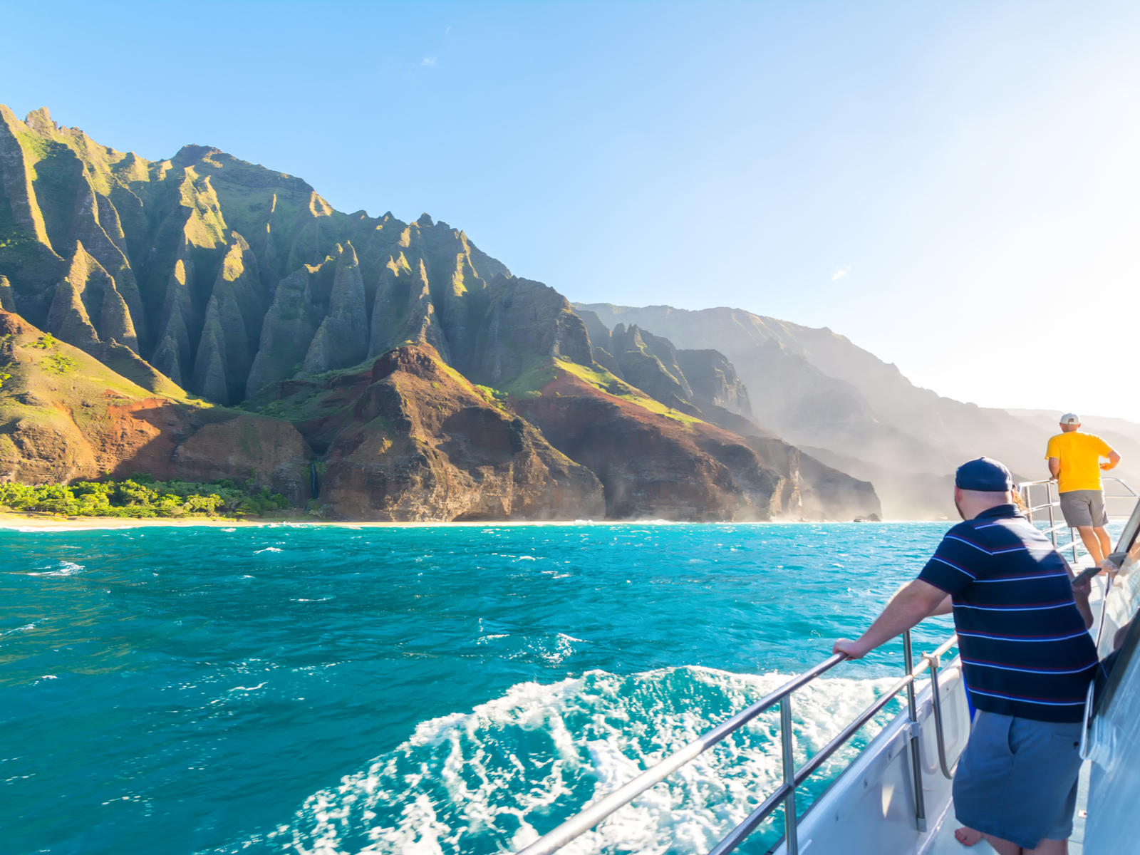 two tourists sailing along the NaPali Coast with its remarkable land formation, considered one of the best things to do in Kauai