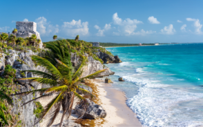 Ruins of Tulum during the best time to visit on a clear day with light waves lapping the shore