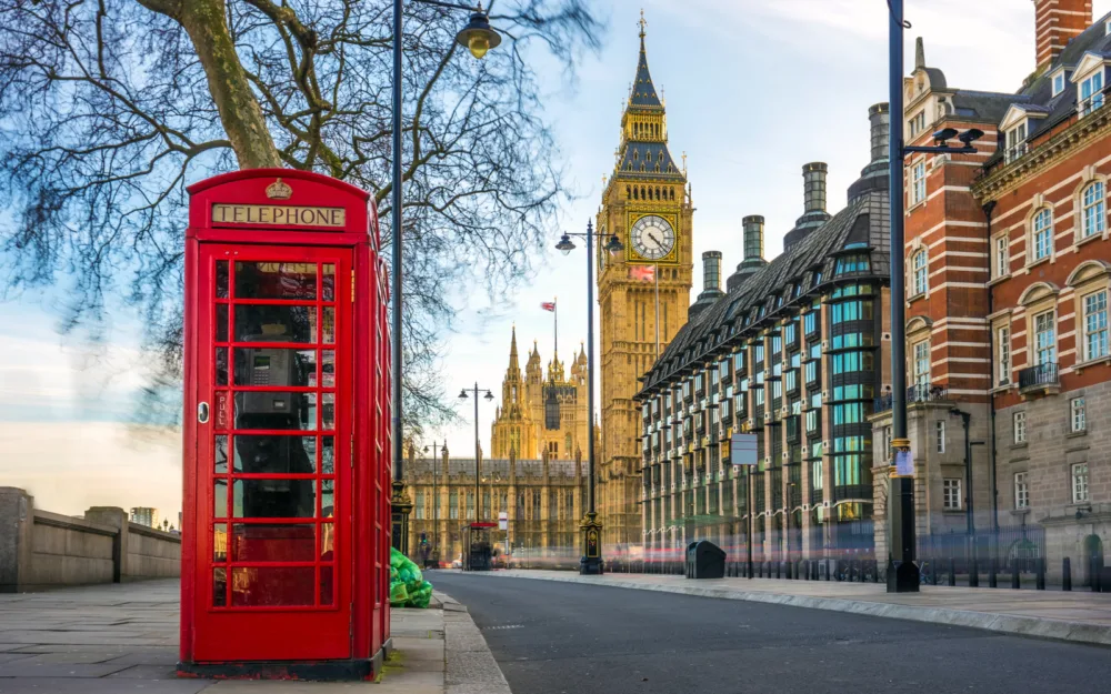 Iconic red telephone booth outside one of the historic buildings with Big Ben in the background during the worst time to visit London