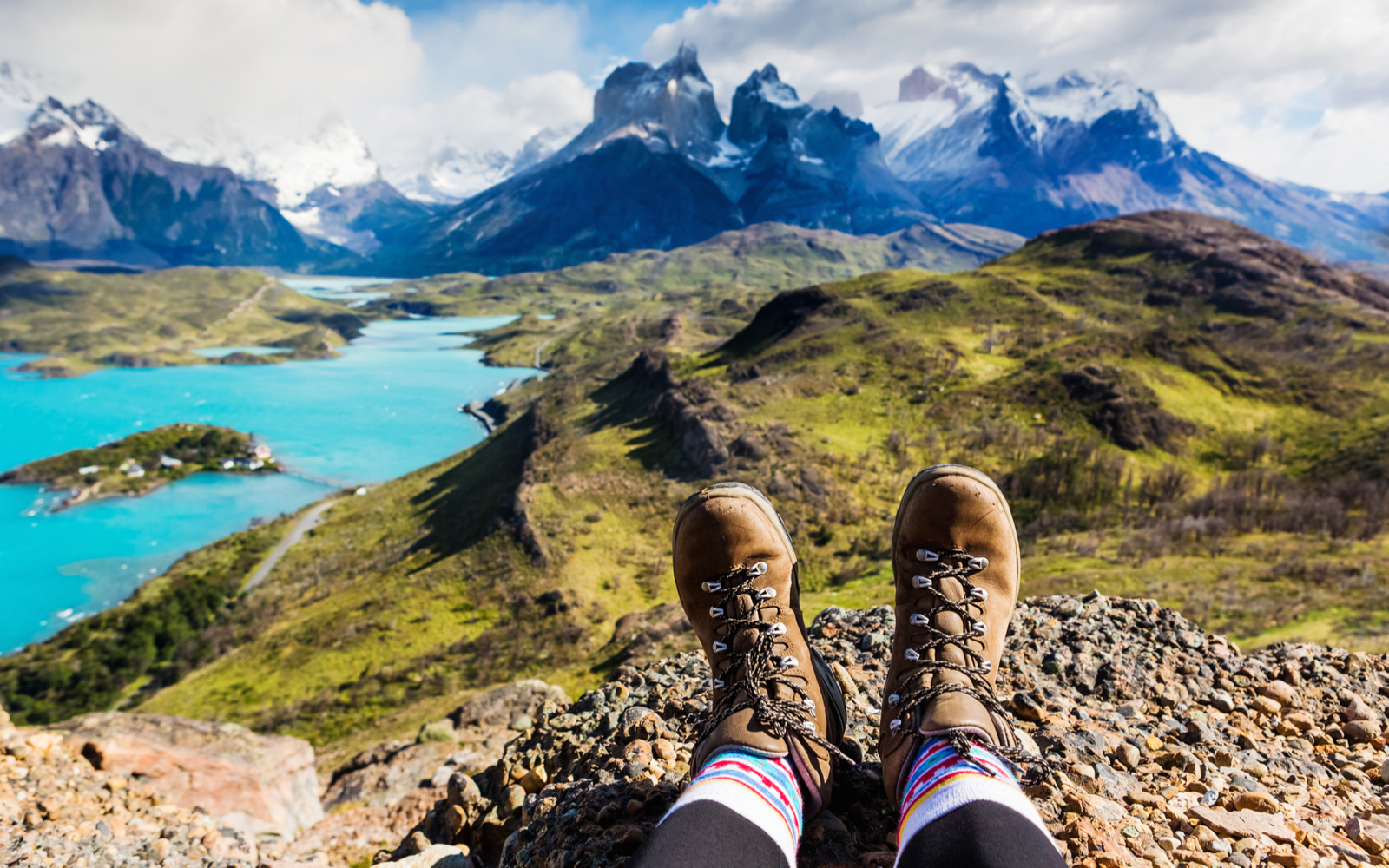 Girl wearing some of the best hiking boots and putting her feet up on a rock at the summit of a mountain