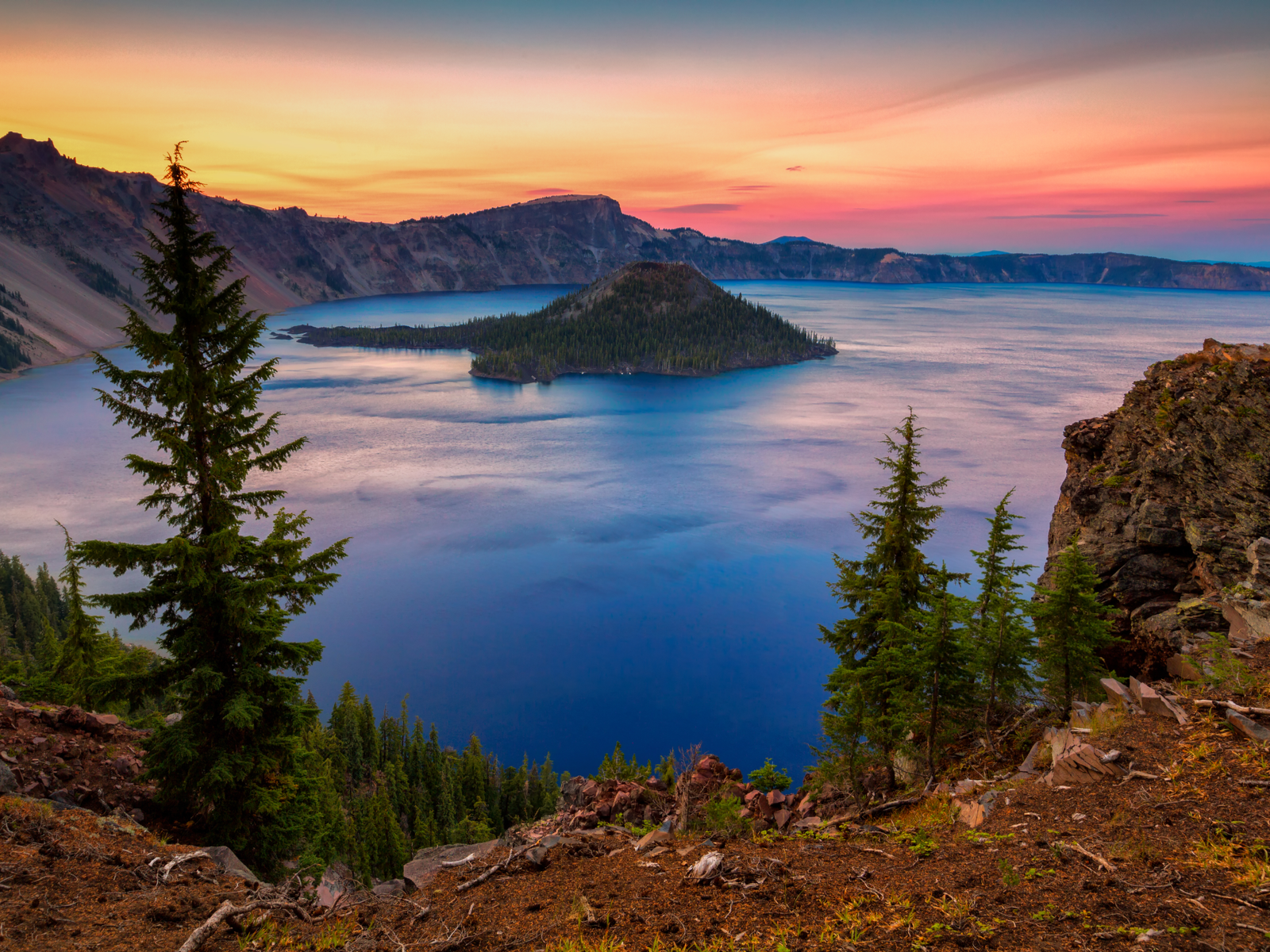 Sunset over the calm waters surrounding a detached portion of land at Crater Lake National Park in Oregon, one of the most beautiful places in the US
