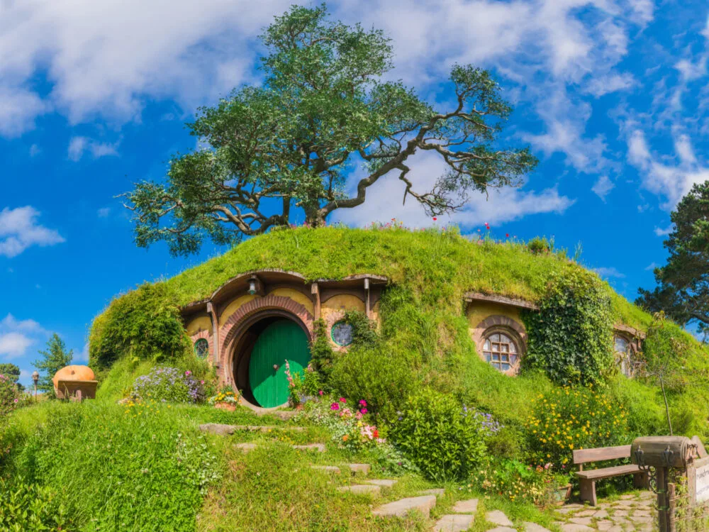Weird-looking house with circular door and windows and grass-covered walls and roofs is one of the Lord of the Rings Filming Locations you can visit