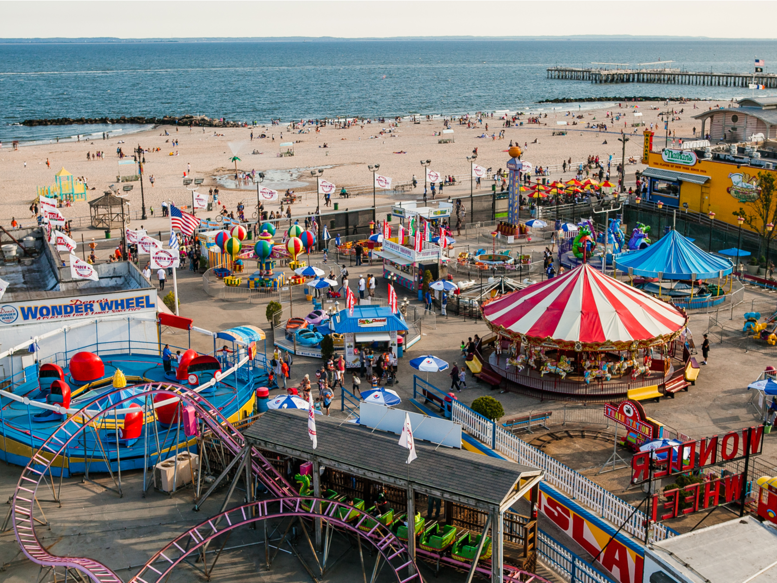 Tourists having a good time at the beach and lively amusement park at Coney Island Beach in New York, one of the best beaches on the East Coast