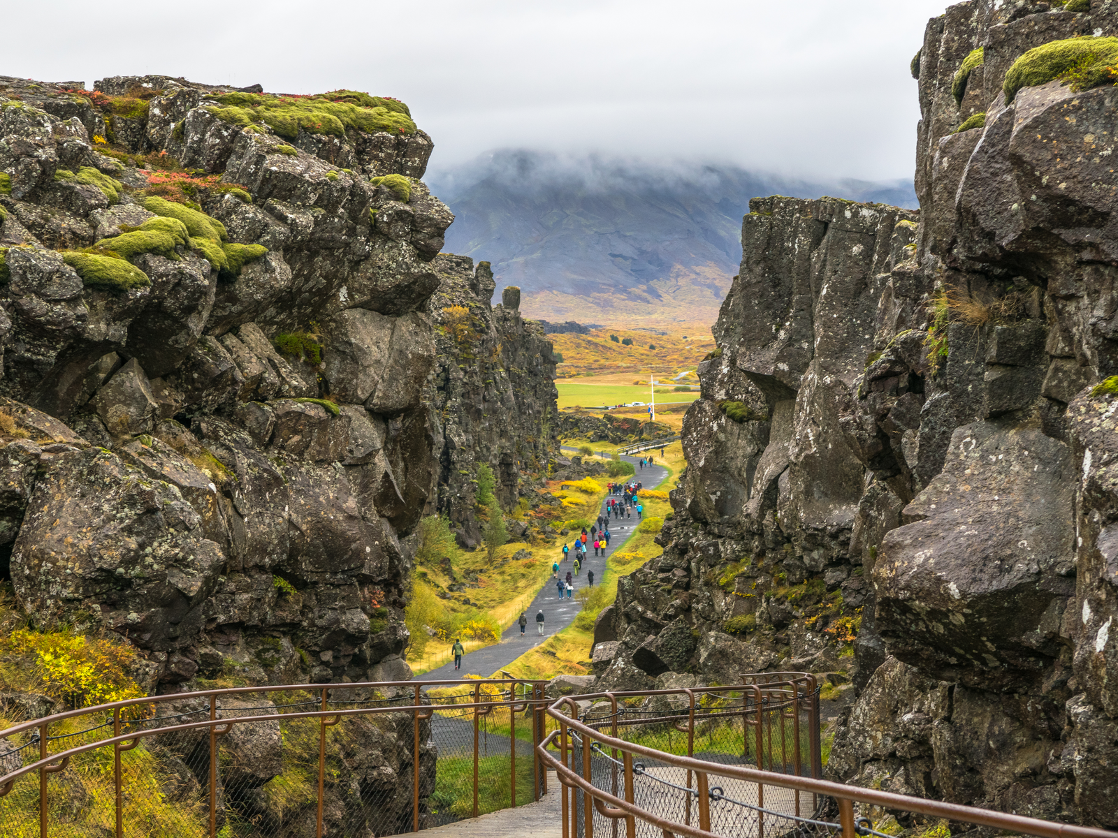 Photographed from a railed footpath as a piece on Game of Thrones filming locations you can visit, people walking beside the Eurasian and North American tectonic plates in Thingvellir National Park, Iceland