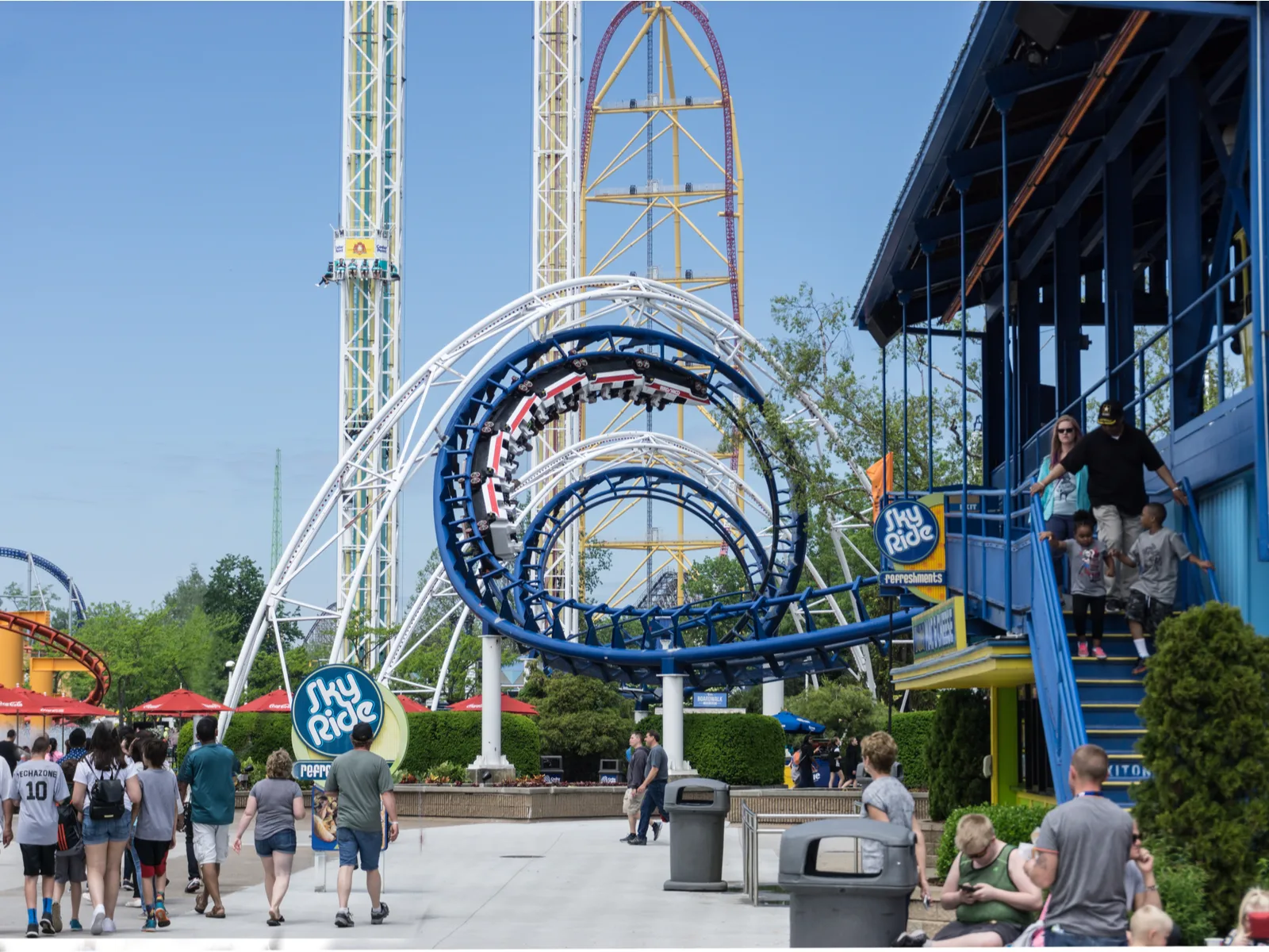 Visitors at Cedar Point in Sandusky, Ohio, considered one of the best roller coaster parks in the US, walk toward the tall Tower Drop and corkscrew Roller Coaster ride