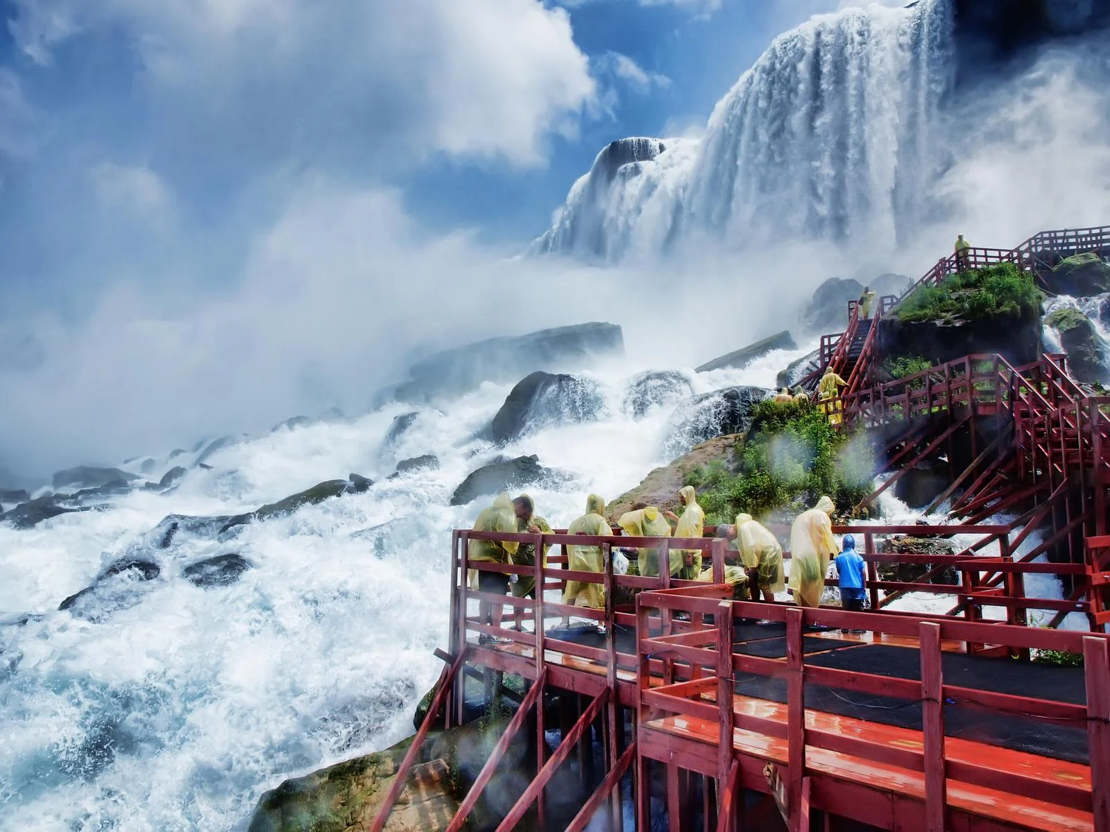 Visitors of Niagara Falls at Niagara Falls State Park, considered one of the most beautiful places in the US, wearing their raincoats as they climb up a boardwalk with stairs near the falls