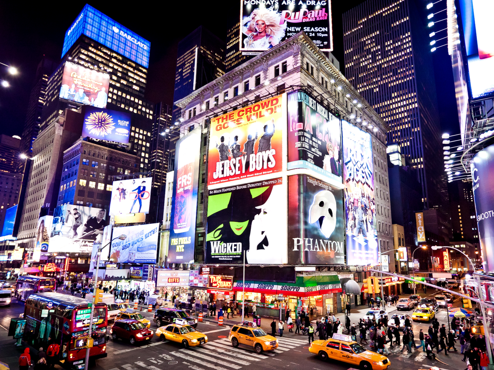 The busy and the bright Time Square in New York at night, considered as one of the most iconic places in America, with Illuminated facades of Broadway theaters