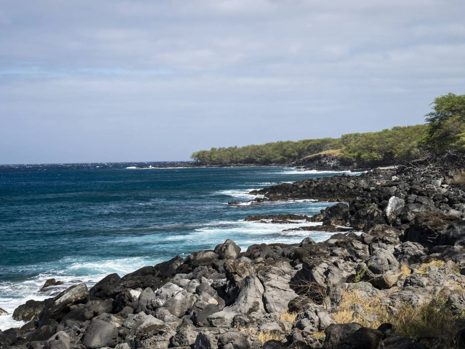 Huge rocks on the coast of Kapa'a Beach State Park, a piece on the best snorkeling spots in Kauai, and its deep blue waters