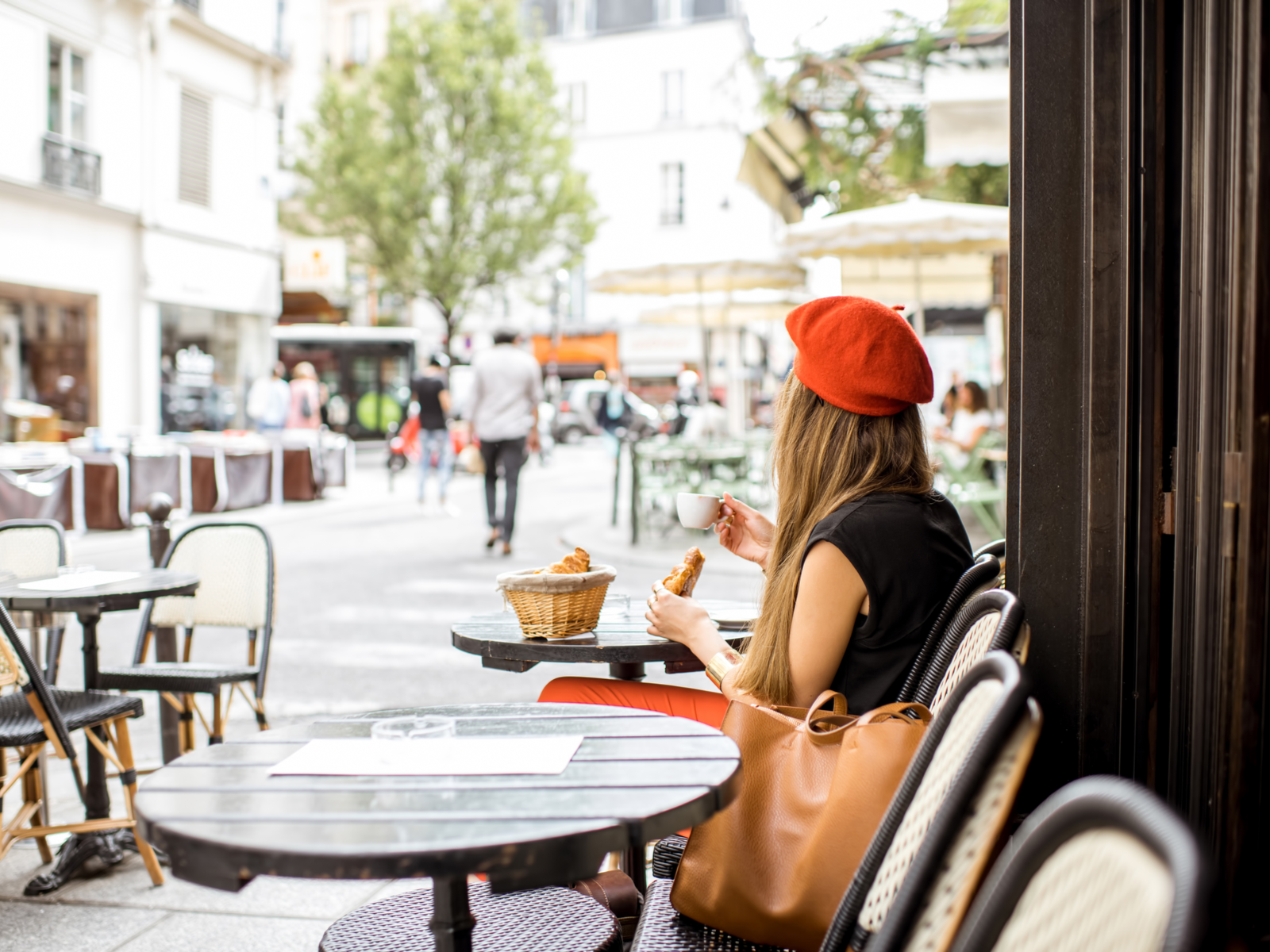 Image of a woman in a red beret in a coffee shop eating bread during the best time to visit Paris