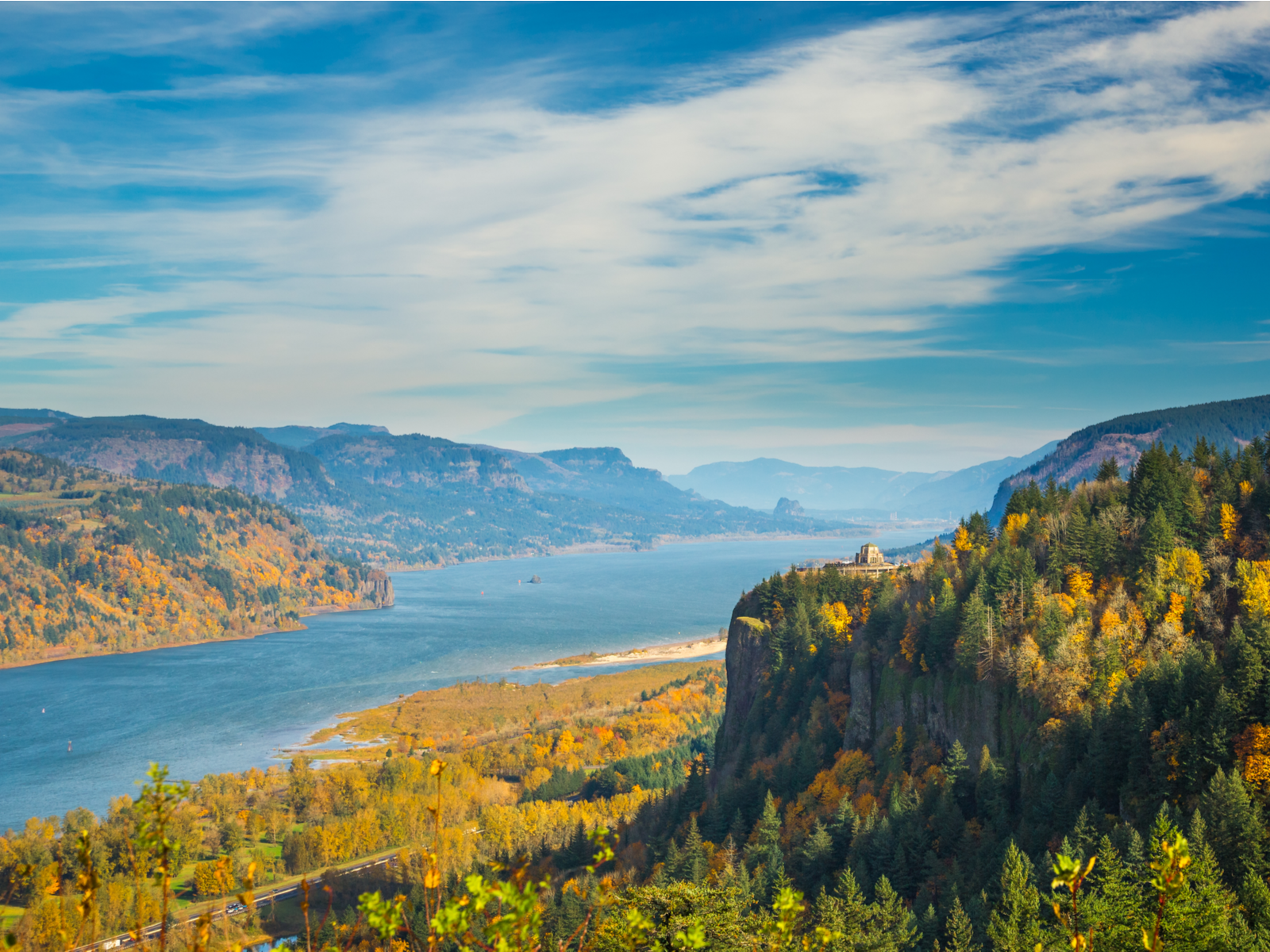 The Crown Point and Vista House surrounded by vibrant foliage in Autumn at Columbia River Gorge National Scenic Area, a piece on the most beautiful places in the US, with the calm flowing river