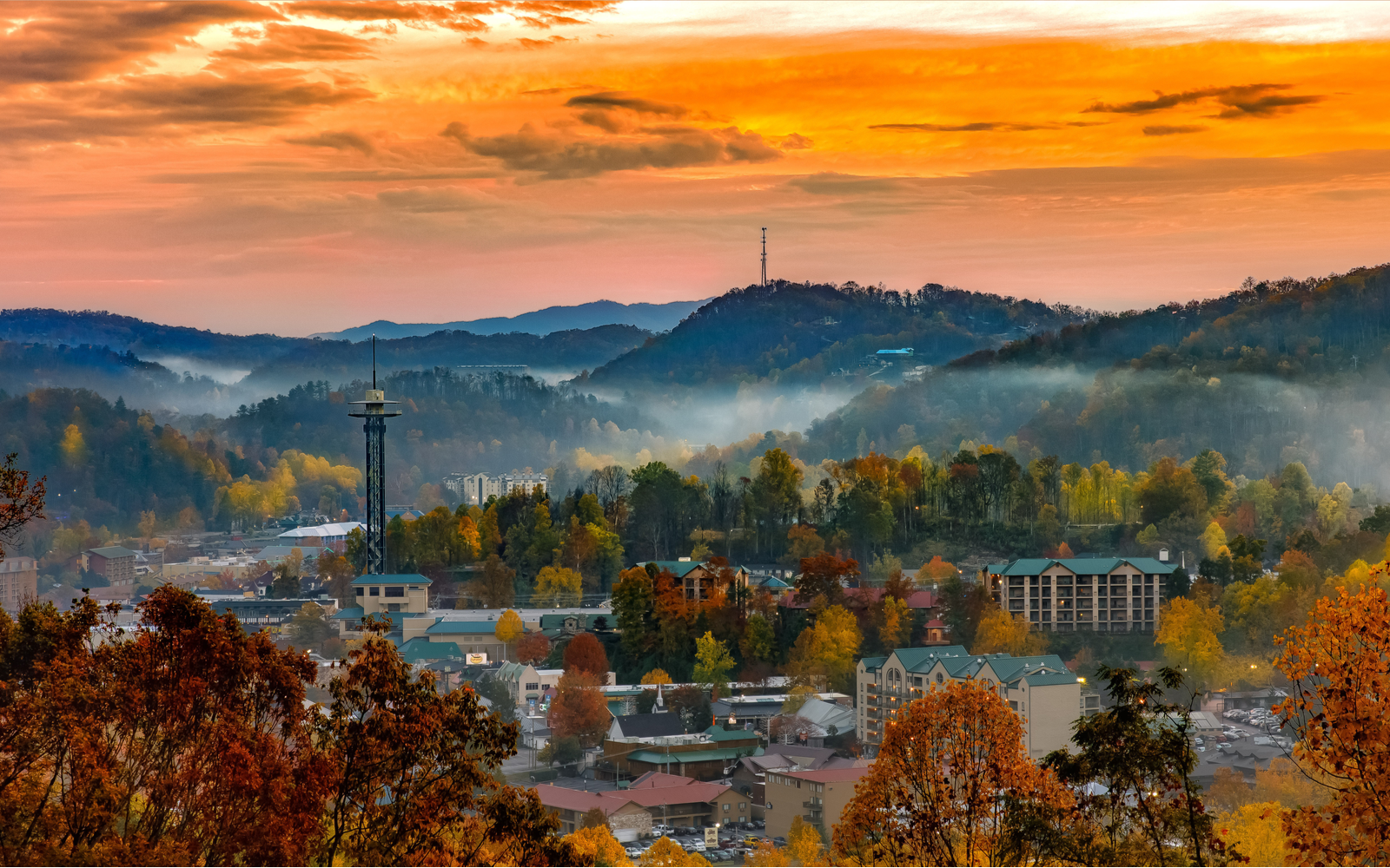 City skyline with an orange sky above the smoky mountains for a piece titled Best Things to Do in Gatlinburg Tennessee