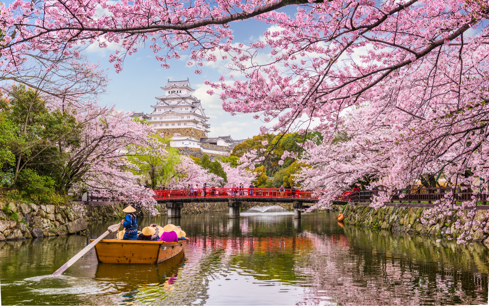 Person in a boat paddling down the river outside Himeji Castle during Spring, the best time to visit Japan