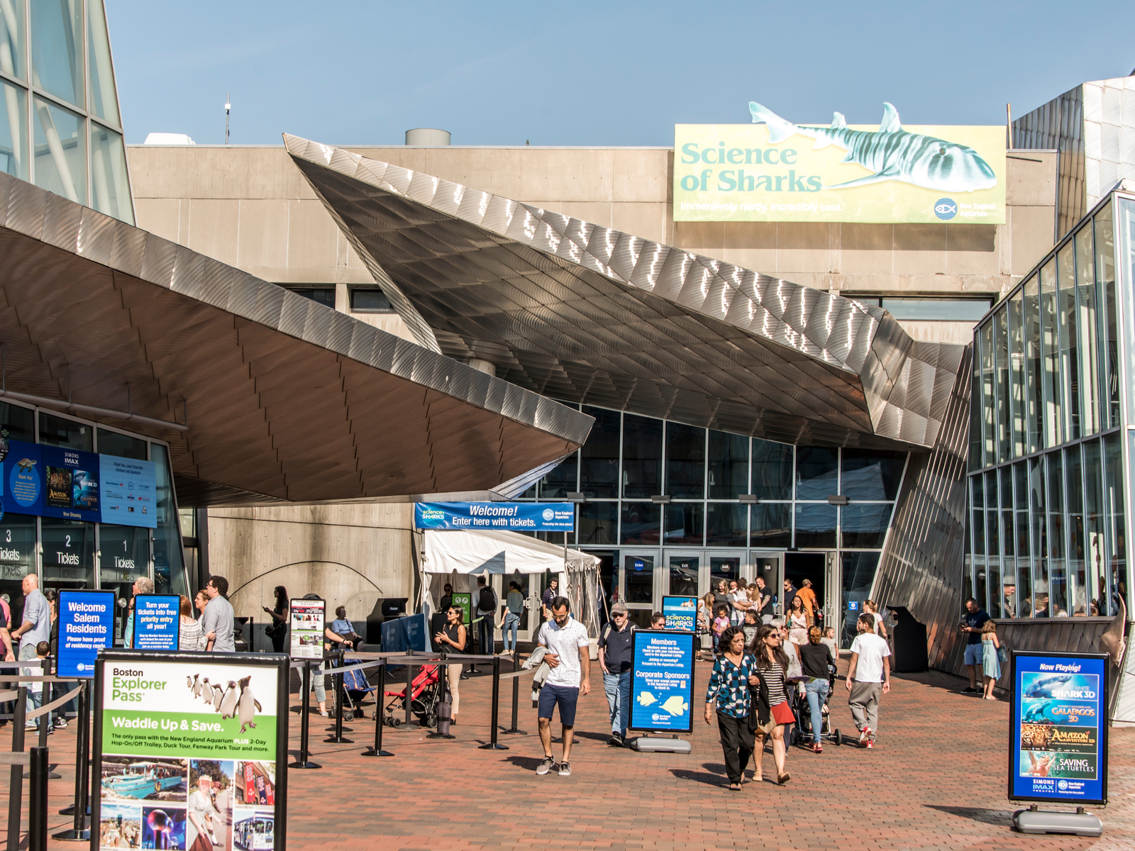 People lining for tickets and exiting the New England Aquarium in Boston, named one of the best aquariums in the US, with its unique architecture and informative signs near the entrance